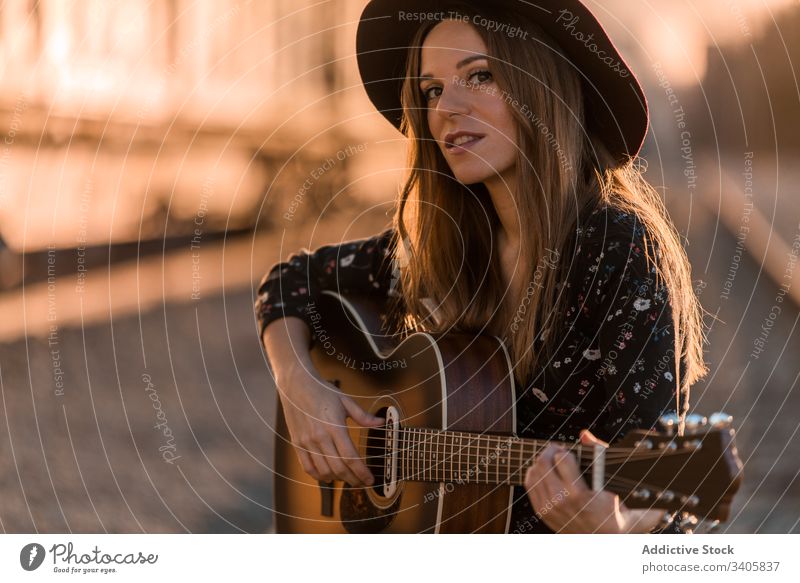 Woman playing guitar on rails woman music travel style perform countryside female instrument acoustic musician song entertain hat boho sound melody lifestyle