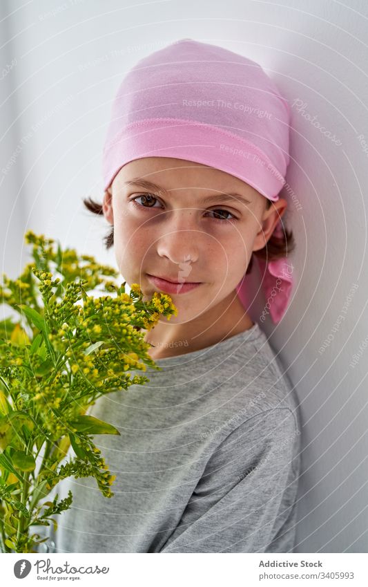Happy cute child with flowers at wall cancer diagnosis vase plant boy sick fight small male patient courageous disease against awareness recovery strength kid
