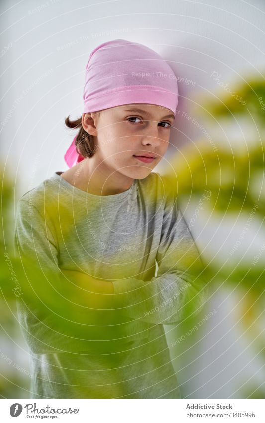 Serious cute child with flowers at wall cancer diagnosis vase plant boy sick fight small male patient courageous disease against awareness recovery strength kid