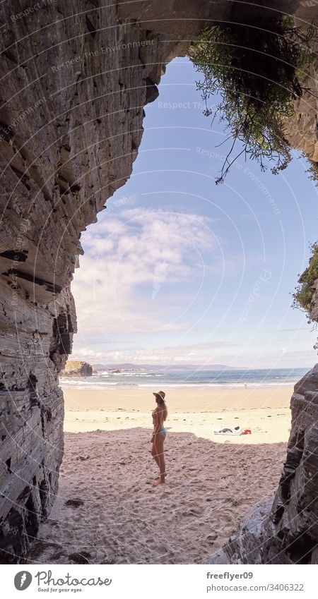 Young woman contemplating a cave made of rocks in Galicia, Spain tourism hiking galicia spain ribadeo castros illas atlantic bay touristic cathedrals cliff