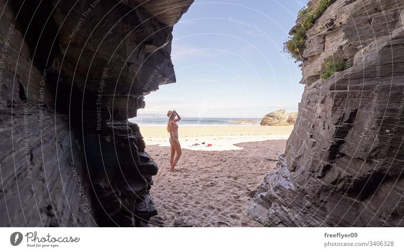 Young woman contemplating a cave made of rocks in Galicia, Spain tourism hiking galicia spain ribadeo castros illas atlantic bay touristic cathedrals cliff