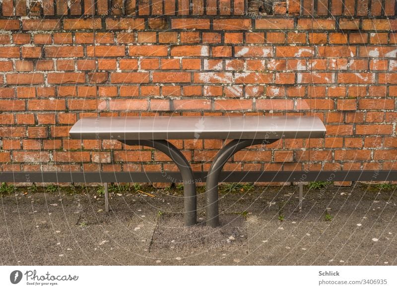 Bus stop modern stainless steel bench in front of brick wall and old chewing gum on the asphalt detail Bench seating furniture Asphalt Chewing gum Modern Old