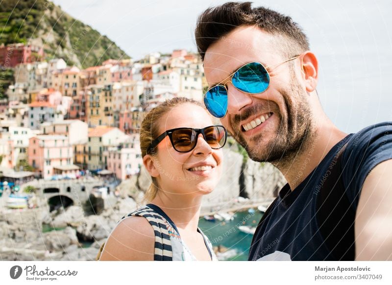 Young couple taking a selfie in Manarola, Cinque Terre in Italy adults boyfriend camera cityscape coast colorful europe fun girl girlfriend happiness happy