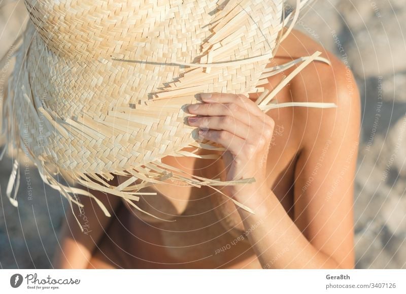 young girl in a straw hat sits on the sand at the beach close up body climate closeup day female female body fingers freedom hands head hide hot naked nature