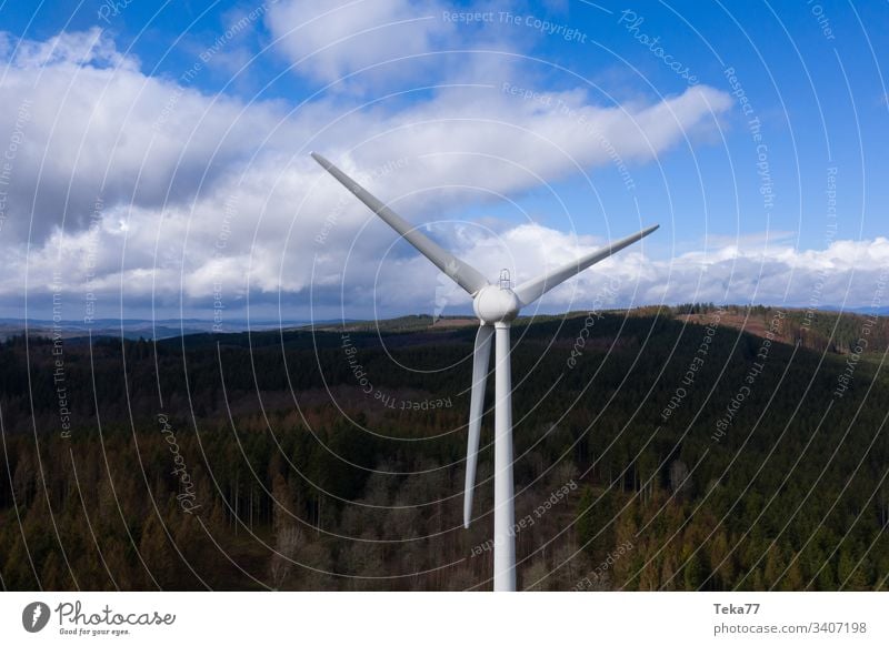 wind wheel in front a dark forest hills landscape and cloudscape air bright cloudscapes electricity energy from above green electricity green energy turbine