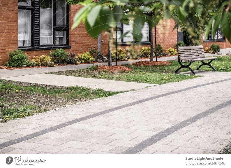 Paved path leading to a modern brick building house pavement paved clean stone tile window windows spring summer tree trees leaves leaf living lifestyle facade
