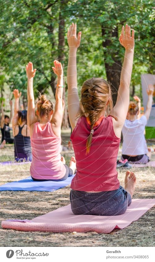 yoga in a park a group of people sitting on yogamates holding th asana bright calm class color event exercise girls group yoga hands hands up health lawn