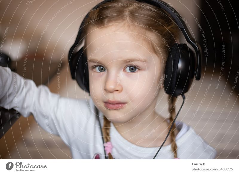 Close up of beautiful blonde little girl listening to music at headphones close up child green eyes Listen to music Relaxation Child To enjoy Joy happiness