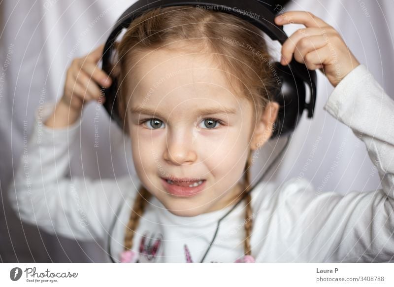 Close up of a beautiful blonde little girl listening to music at headphones smile happy young beauty child kid daughter fun cute enjoy isolated person