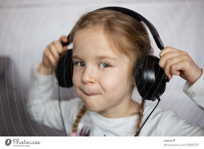 Close up of a beautiful blonde little girl listening to music at headphones smile happy young beauty child kid daughter fun cute enjoy isolated person