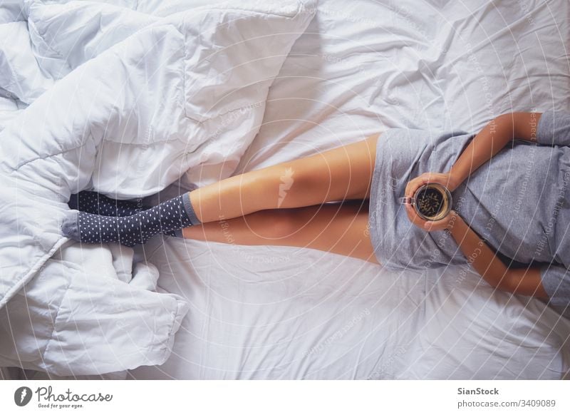 Female legs in white socks in white linens bed, top view Stock Photo