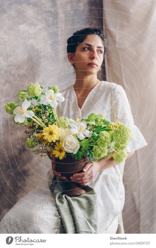 Young woman in a white dress holding vase with flowers. Vintage, romantic concept. bouquet girl metal sit sitting chair soft light beautiful vintage wedding