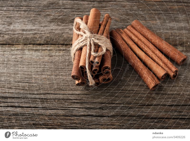 brown cinnamon sticks tied in a bun on a gray wooden background, tasty and fragrant spice food sweet ingredient closeup dessert aroma aromatic table healthy