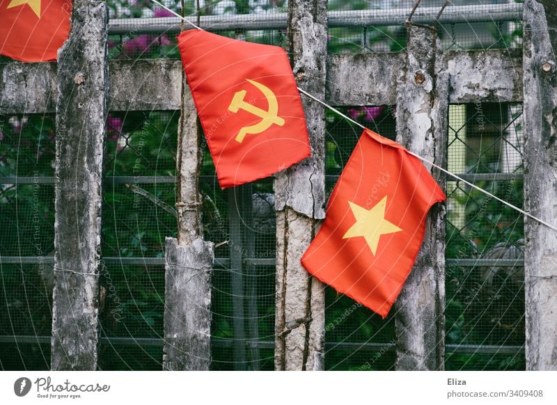 A fence on which the Vietnamese national flag, with hammer and sickle in yellow on a red background, hangs; symbol of communism Communism Socialism Ensign