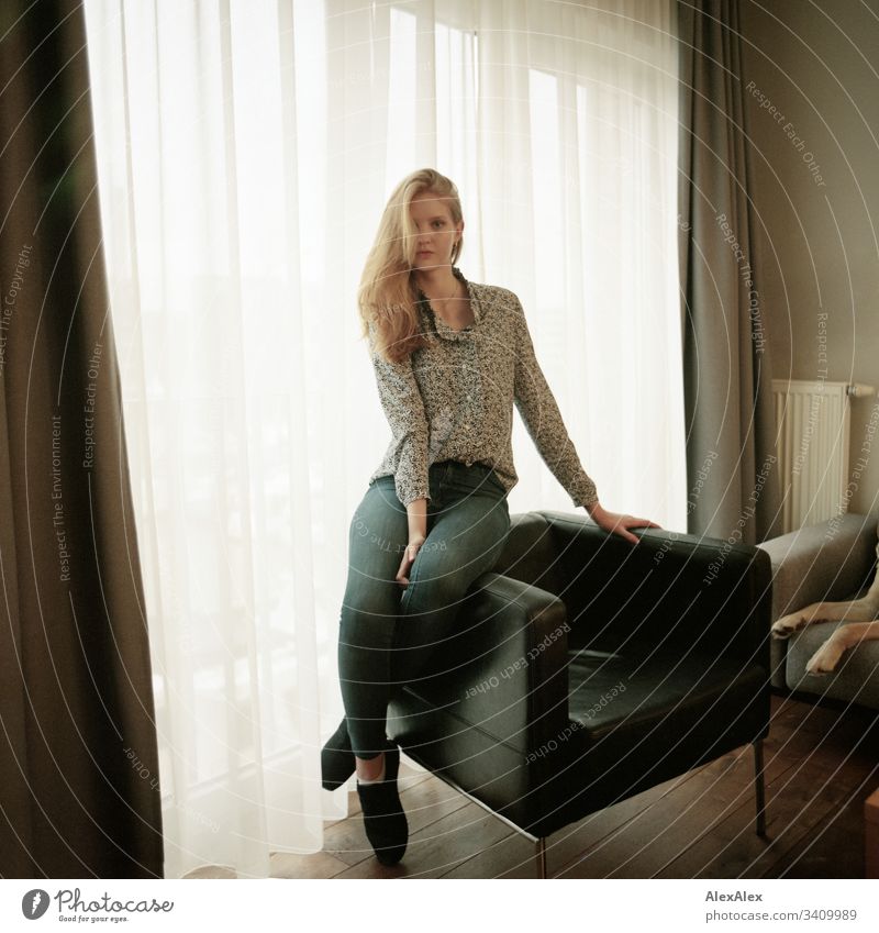 Portrait of a young woman on an armchair in front of the window Woman Girl Blonde Beautiful youthful Slim daintily Elegant Lifestyle dwell Flat (apartment)