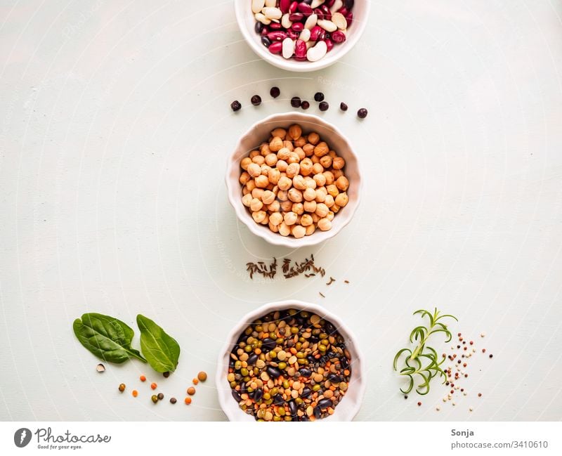Chick peas and various legumes in white bowls in a row on a light kitchen table with spices, flat layer, vegetable protein, healthy food chickpea Bean Legume