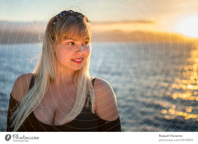 Portrait of a blonde woman with the sea in the background and lit by the evening sunlight. beach beautiful young beauty summer portrait sunset ocean happy hair