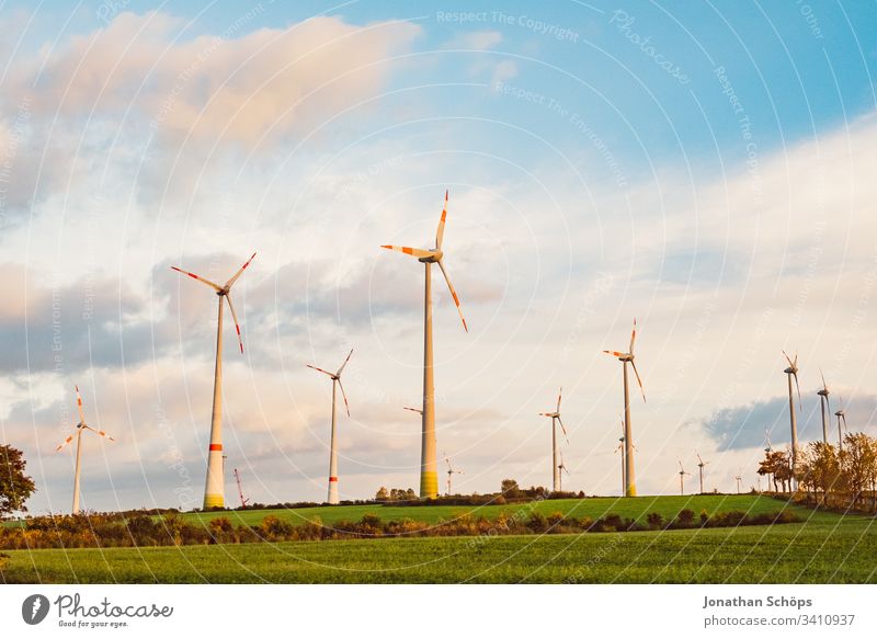 ecological renewable green energy wind power station on a field in evening sun alternative background blue change clean climate change cloud countryside design