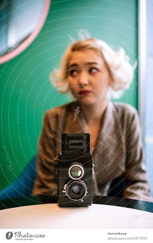 Old vintage film two lens camera with the blurred female silhoutte in the back, selective focus shot table silhouette figure woman hand photographer retro