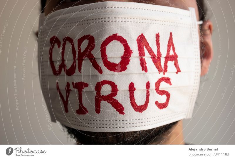 Closed up to a CORONAVIRUS man patient with beard using a white face mask with red CORONAVIRUS inscription. Concept photography COVID-2019 2019-ncov alert