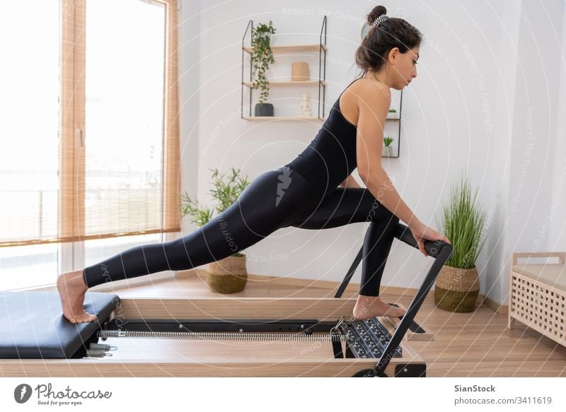 Woman on a reformer bed doing hip opening pilates yoga exercises using  straps in a gym workout in a health and fitness concept Stock Photo - Alamy