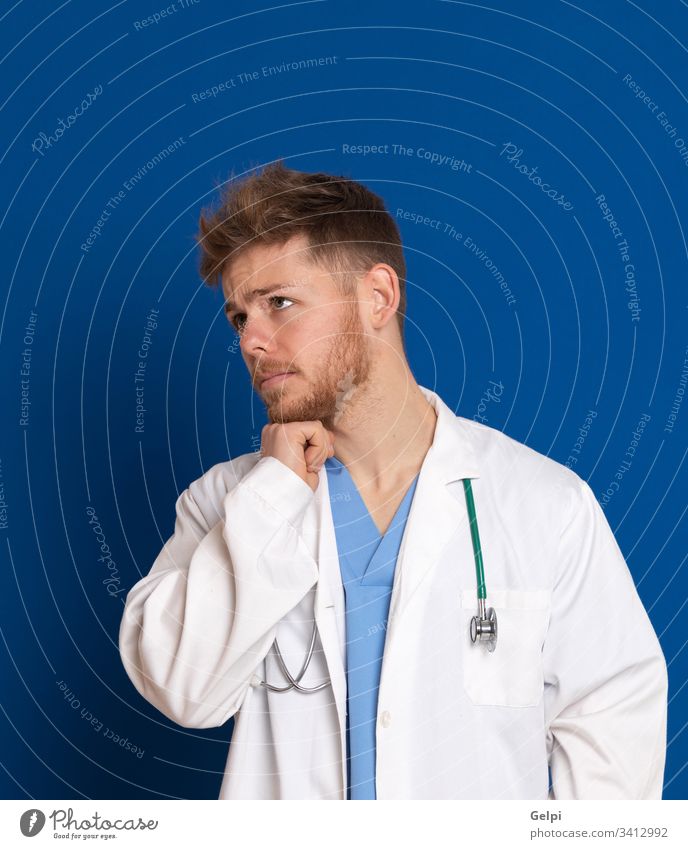 Attractive doctor with white lab coat on a blue background uniform health review worried worry thoughtful pensive think imagine imagination sad negative idea