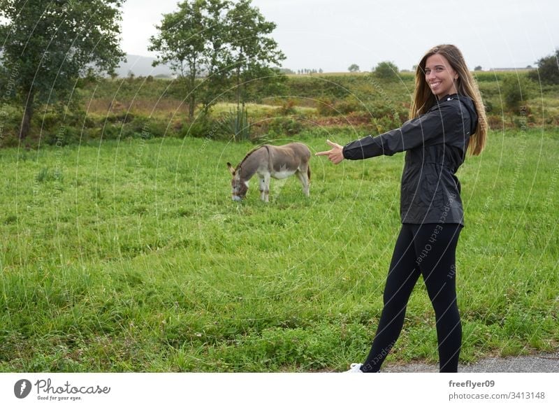 Young woman with a donkey on a grass field farm outdoors food offspring mammal feeding look farm animal cute nature rest green eating head mule face adorable