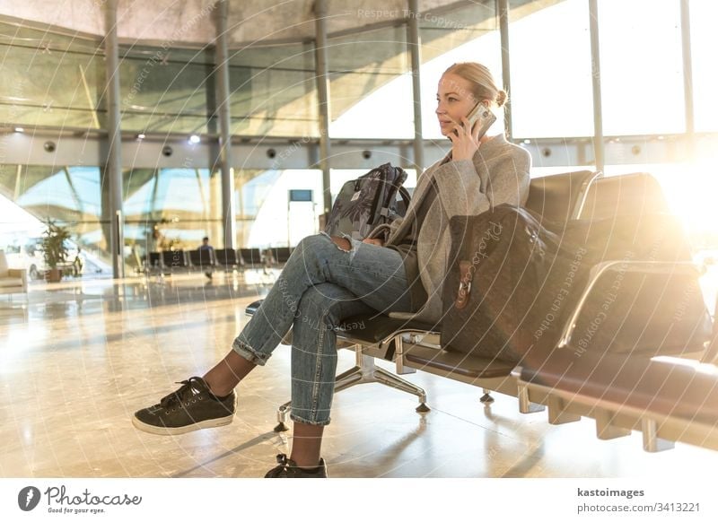 Female traveler talking on her cell phone while waiting to board a plane at departure gates at airport terminal. female woman business flight baggage luggage