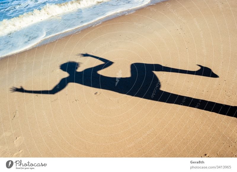 shadow of a dancing girl on the sea sand on the beach near the sea black blue dancing shadow hands rest shadow of a girl shadow of a woman shadow on the sand