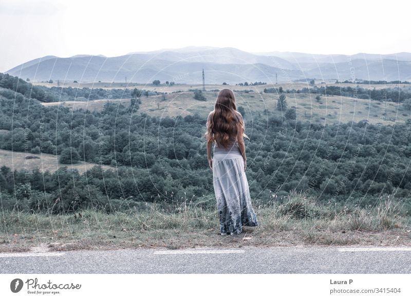 Lonely woman with long hair looking at a hill carefree believe spirit thoughts wind dream day background grass adult horizon person think stress quiet view