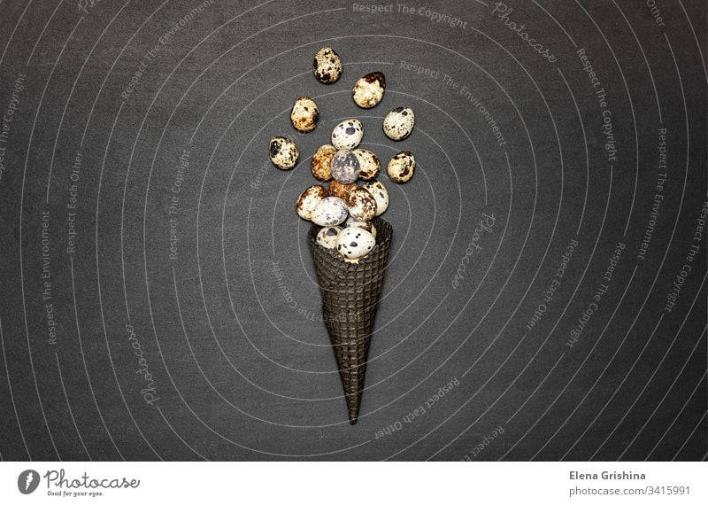 Dark waffle cone with easter eggs on a black background. Space for text. View from above. moody art quail eggs april close-up layout happy easter stylish