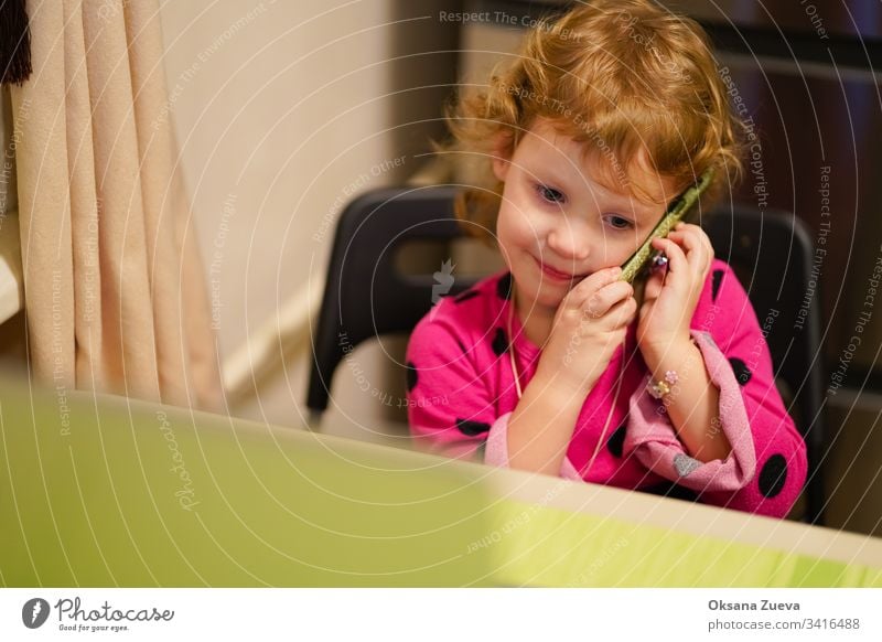 Curly little girl talking with her grandmother on the phone. She smiles, tells the news how she is doing. adorable attractive baby beautiful candid cheerful