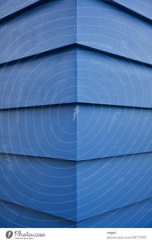 Corner of a building whose facade is covered with blue painted wooden planks. Blue Abstract Facade Building Wood Architecture edge lines geometric background