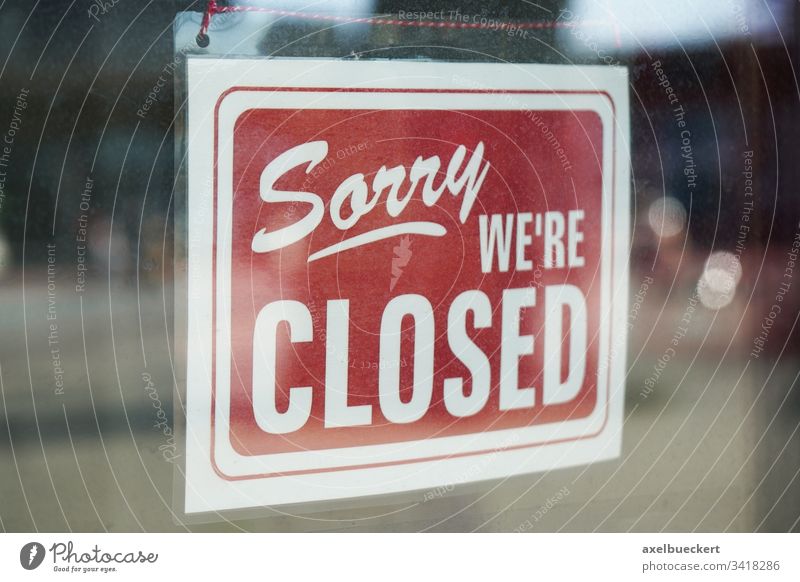 Sorry we're closed sign behind dirty glass door sorry we are closed corona coronavirus business lockdown economy bankruptcy window store shop information