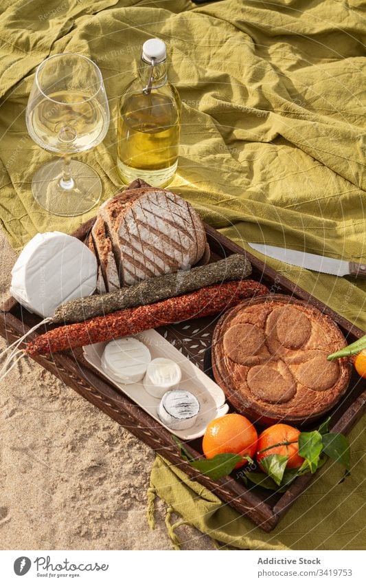 Pastry and tangerines with cheese and sausages near wine during picnic food blanket beach pie bread delicious tasty fresh meal snack gourmet drink beverage