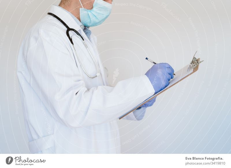 unrecognizable doctor wearing protective mask and gloves indoors. writing notes on a folder. Corona virus concept man professional corona virus hospital working