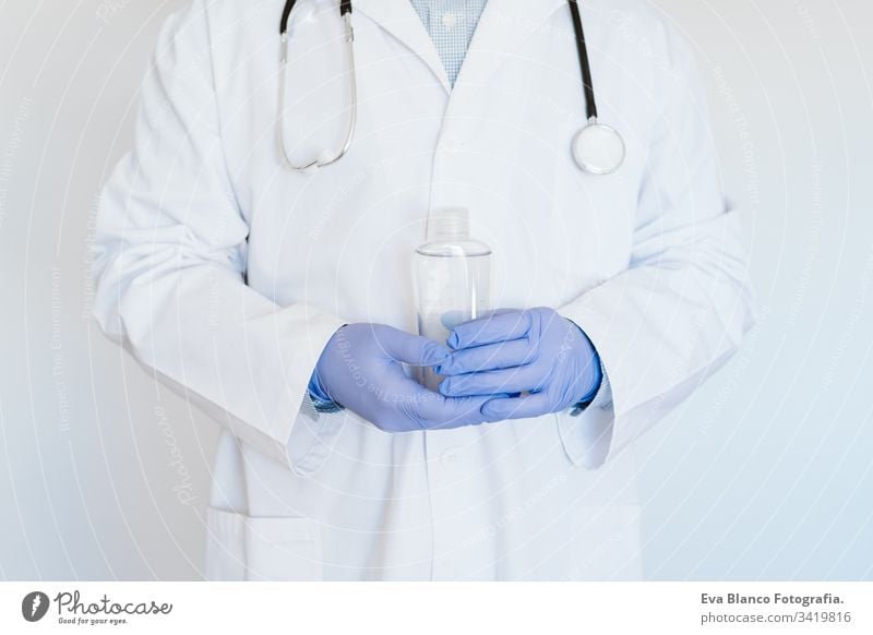 caucasian doctor wearing protective mask and gloves indoors. Holding an alcohol gel or antibacterial disinfectant. Hygiene and corona virus concept man