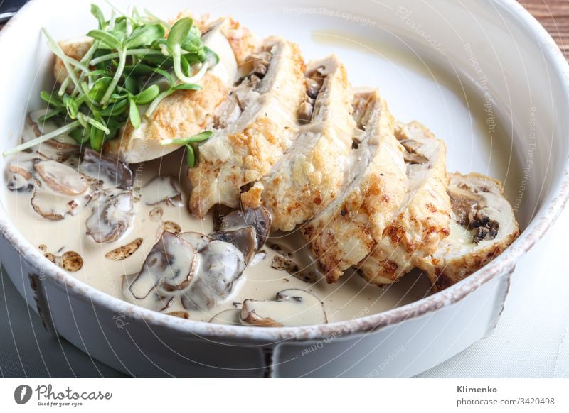 Chicken breast roll with mushrooms. Next to the champignon sauce. On a dark background. Decorated with microgreen. food meat easter dinner meal plate pork