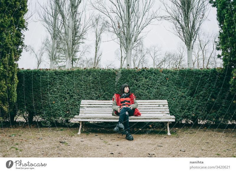 Young woman relaxing in a green park in winter outdoor solitude alone loneliness nature natural cold youth fresh real candid rest resting calm tranquiltiy