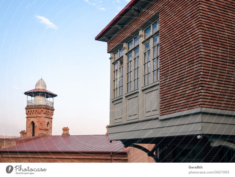 tall old tower and modern building with windows in Georgia Caucasus architecture blue brick city clouds color corner day dome house religion retro roof sky