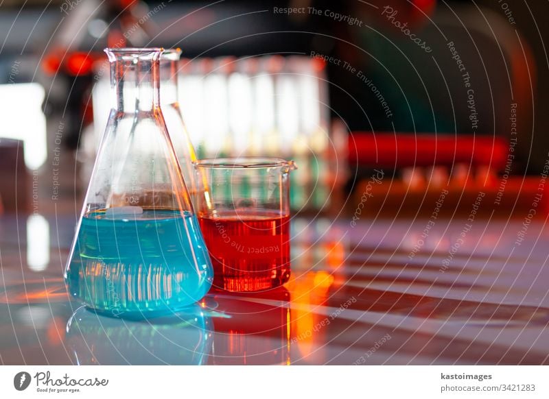 Illuminated laboratory flask filed with colorful chemical solutions with shadows on the table. Laboratory, science, reaserch, chemistry... consept. glassware