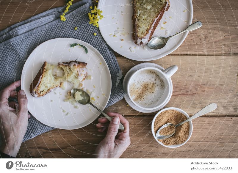 Anonymous woman having breakfast with delicious fresh pie cake dessert lemon coconut slice piece cup coffee table plate hand arm wooden ingredient serve