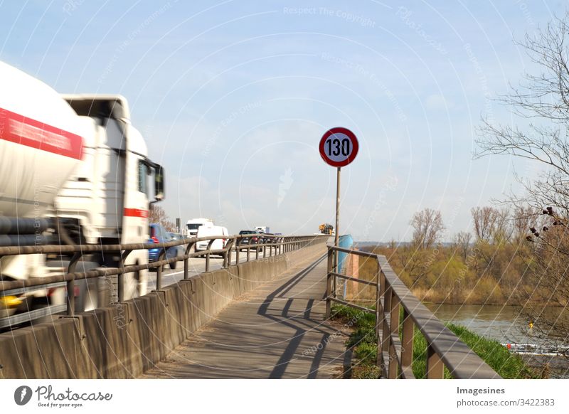 130 Motorway sign - traffic sign in road traffic. Speed limit, German motorway km / h. Motorway in Germany with vehicles - cars and trucks - trucks, blue sky background. Traffic safety, concept