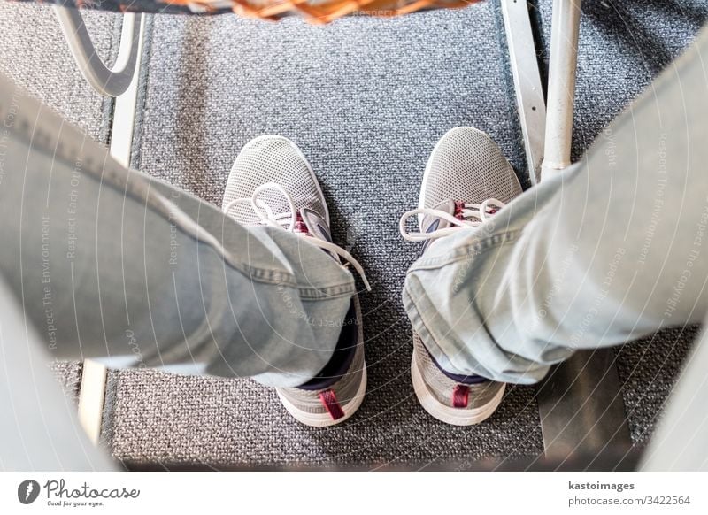 Male passenger with lack of leg space on long commercial airplane flight. Focus on casual sporty sneakers seat journey legs transport transportation travel