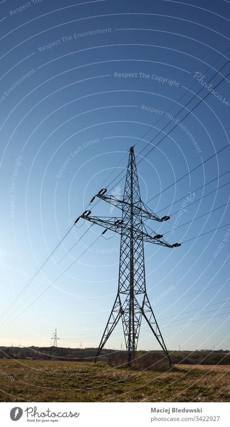High voltage transmission tower on a field against the sun. industry sky power tower electricity pylon energy cable technology structure engineering wire