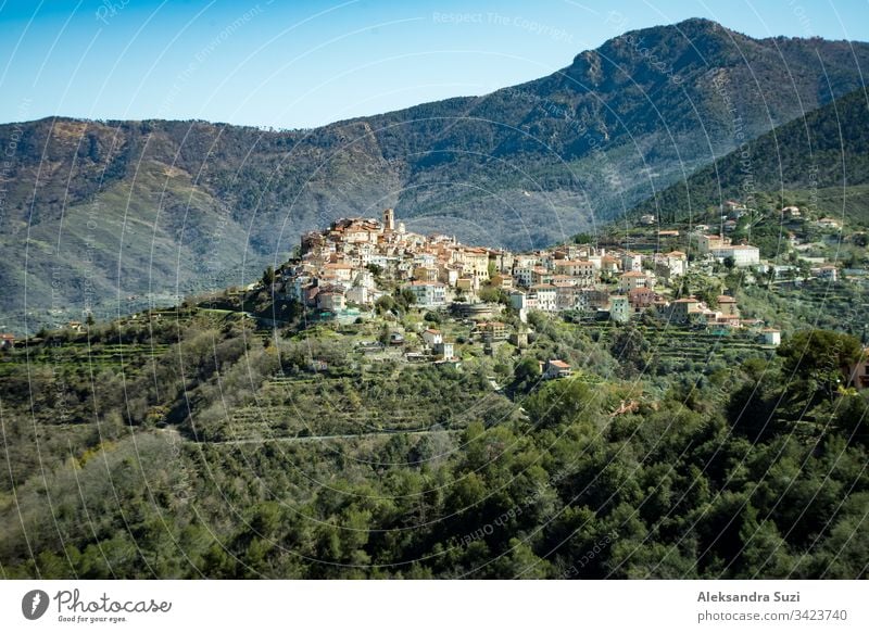 Panoramic top view of Alps mountains in fog and clouds, valley with clouds. Green slopes and fields. Almond trees in bloom. Medieval buildings of Perinaldo town, Liguria, Spring Italy