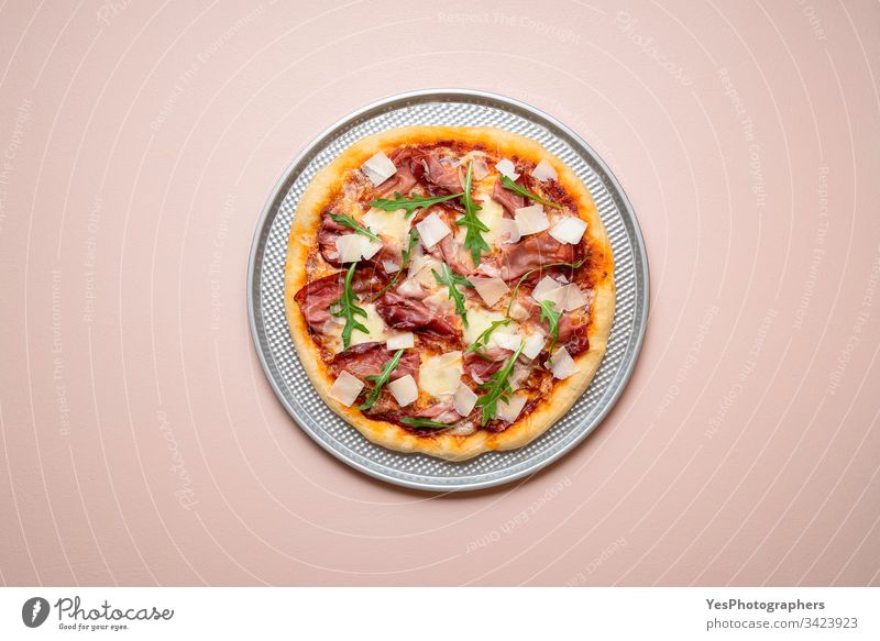 Pizza prosciutto on a baking tray. Whole ham pizza with arugula Italian above view carbs cheese and ham cuisine dinner european famous fast food finger food