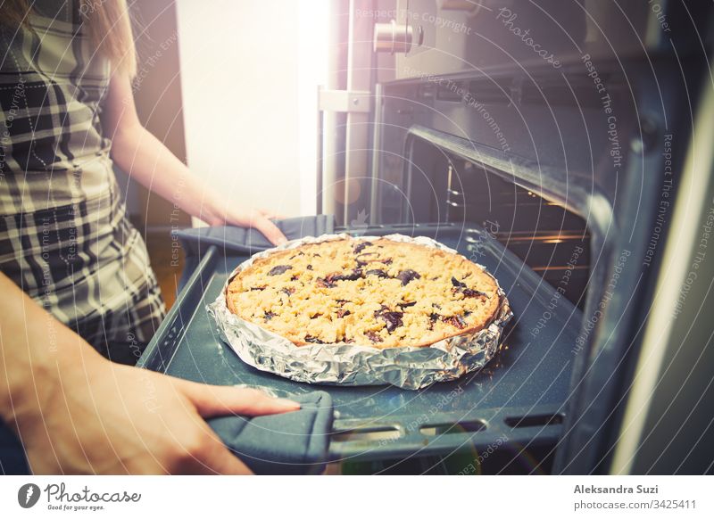 Woman hands taking out tray with pastry from oven, closeup. Fresh homemade delicious plum pie. bake cake cook cooking cuisine dessert female food fresh fruit