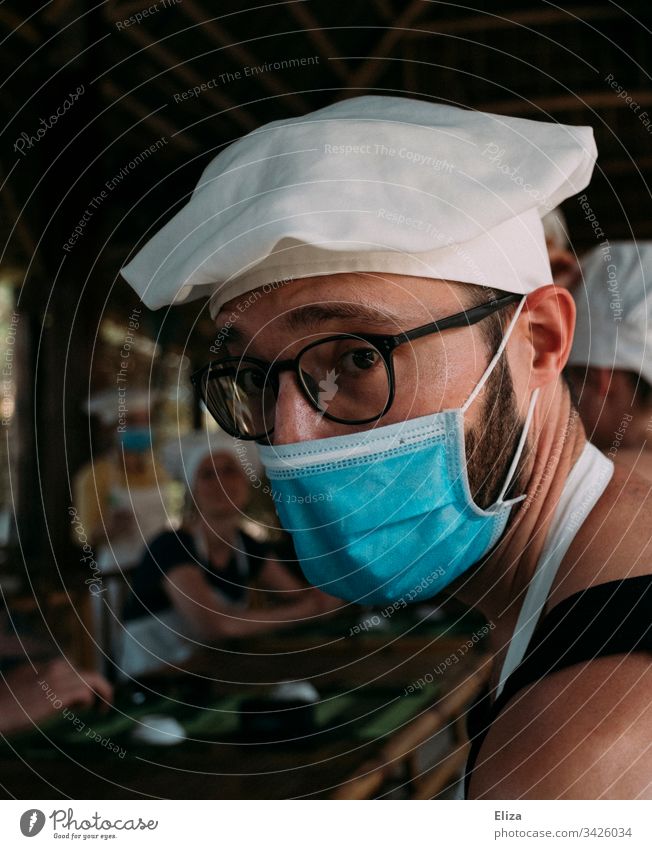 A man with a face mask and chef's hat at a cooking class corona Man Virus Mask Face mask Mouth and nose mask medical mask Infection covid-19 guard sb./sth.