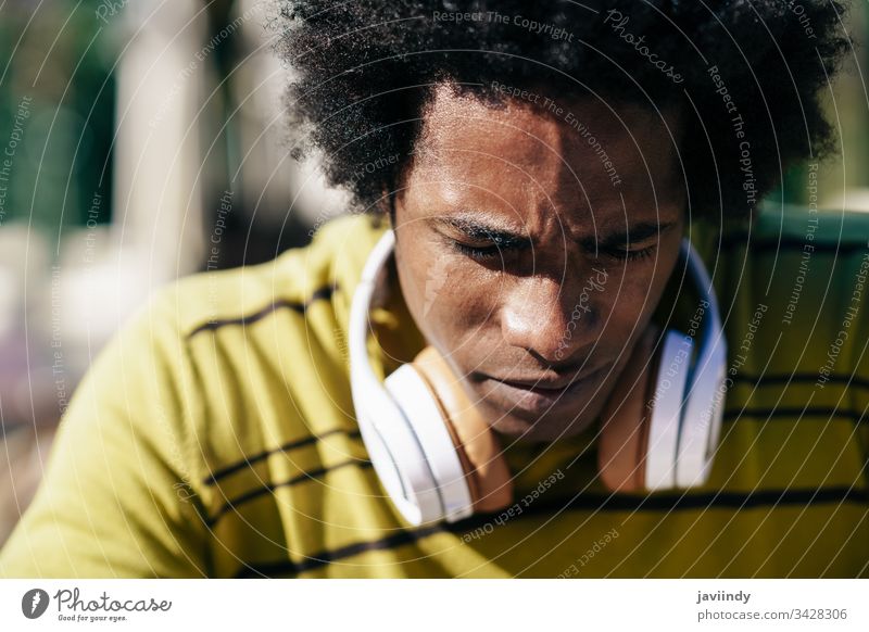 Close-up portrait of serious black man looking down. afro concerned thoughtful pensive hair african male face adult american person casual guy attractive